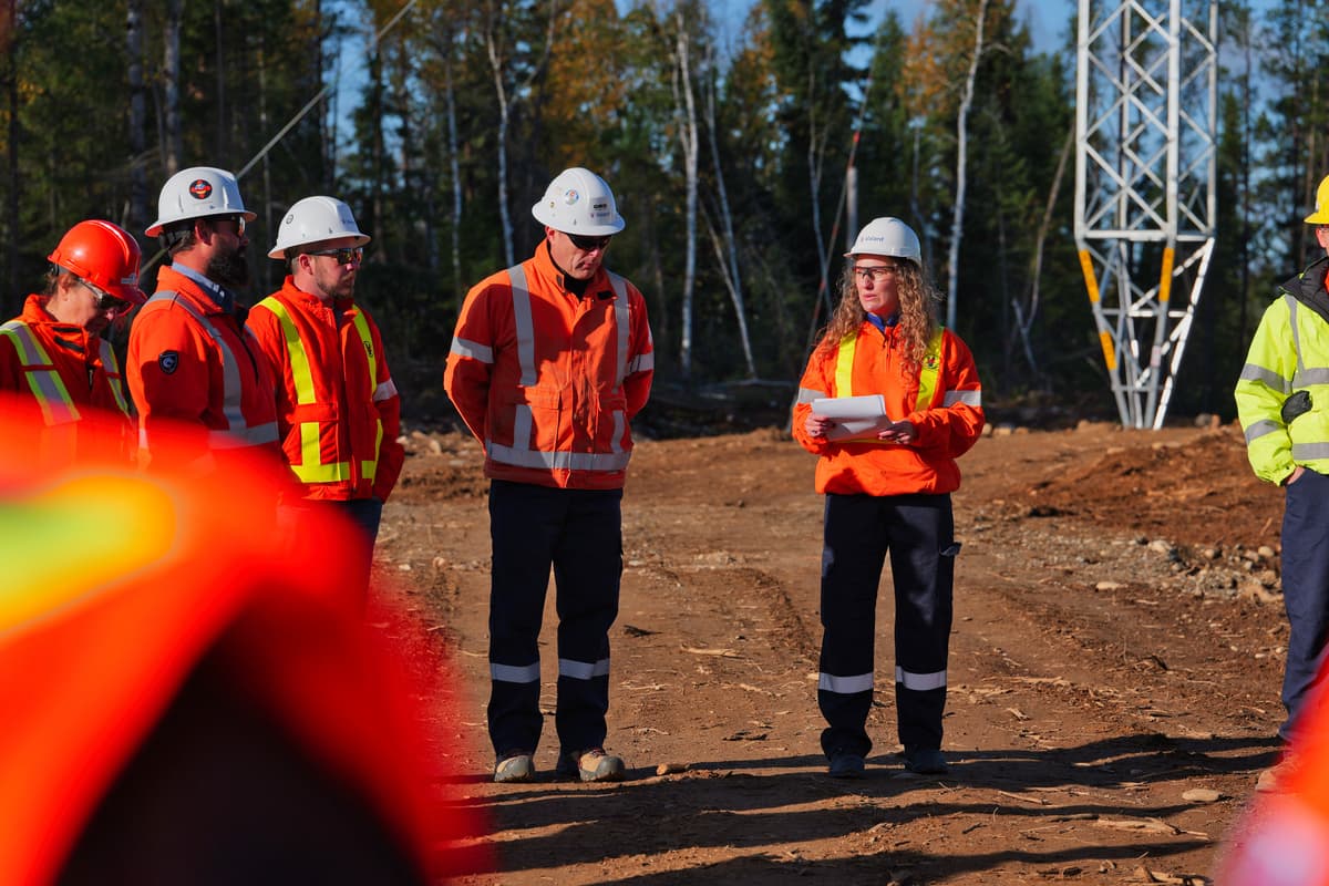 Crews and community monitors gather at the base of a transmission tower on the right-of-way.